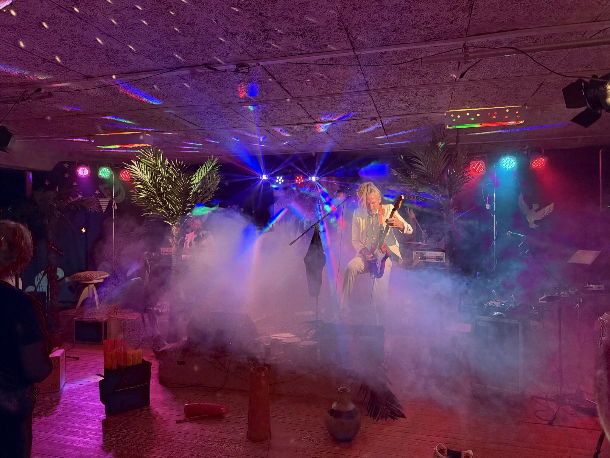 Guitarist på scenen omgivet af røg og farverige lys